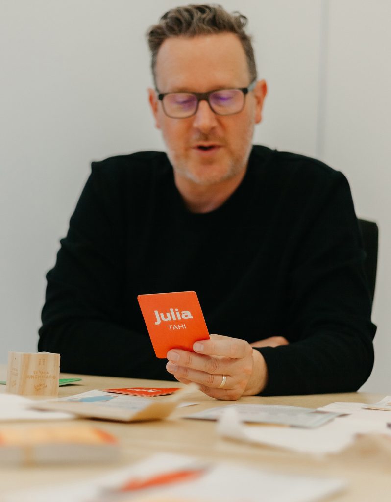 A man holds a playing card from the game Taurite.