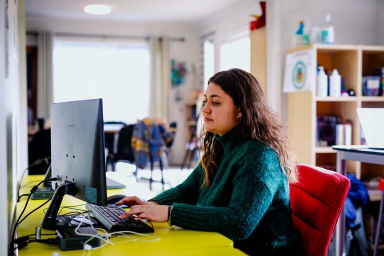 A young Māori woman works at a laptop.